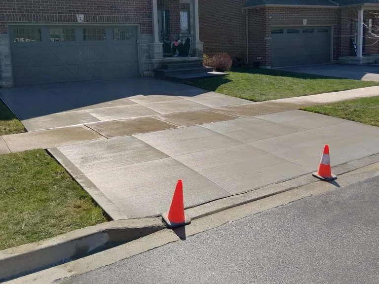Newly installed concrete driveway in front of a brick home